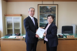 写真：播磨議長に報告書を手渡す立身副委員長