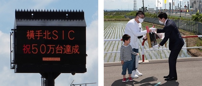写真：利用台数50万台達成を知らせる電光掲示板と記念品を受け取る木元さん